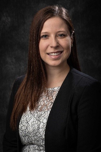 Woman smiling in black jacket and patterned blouse
