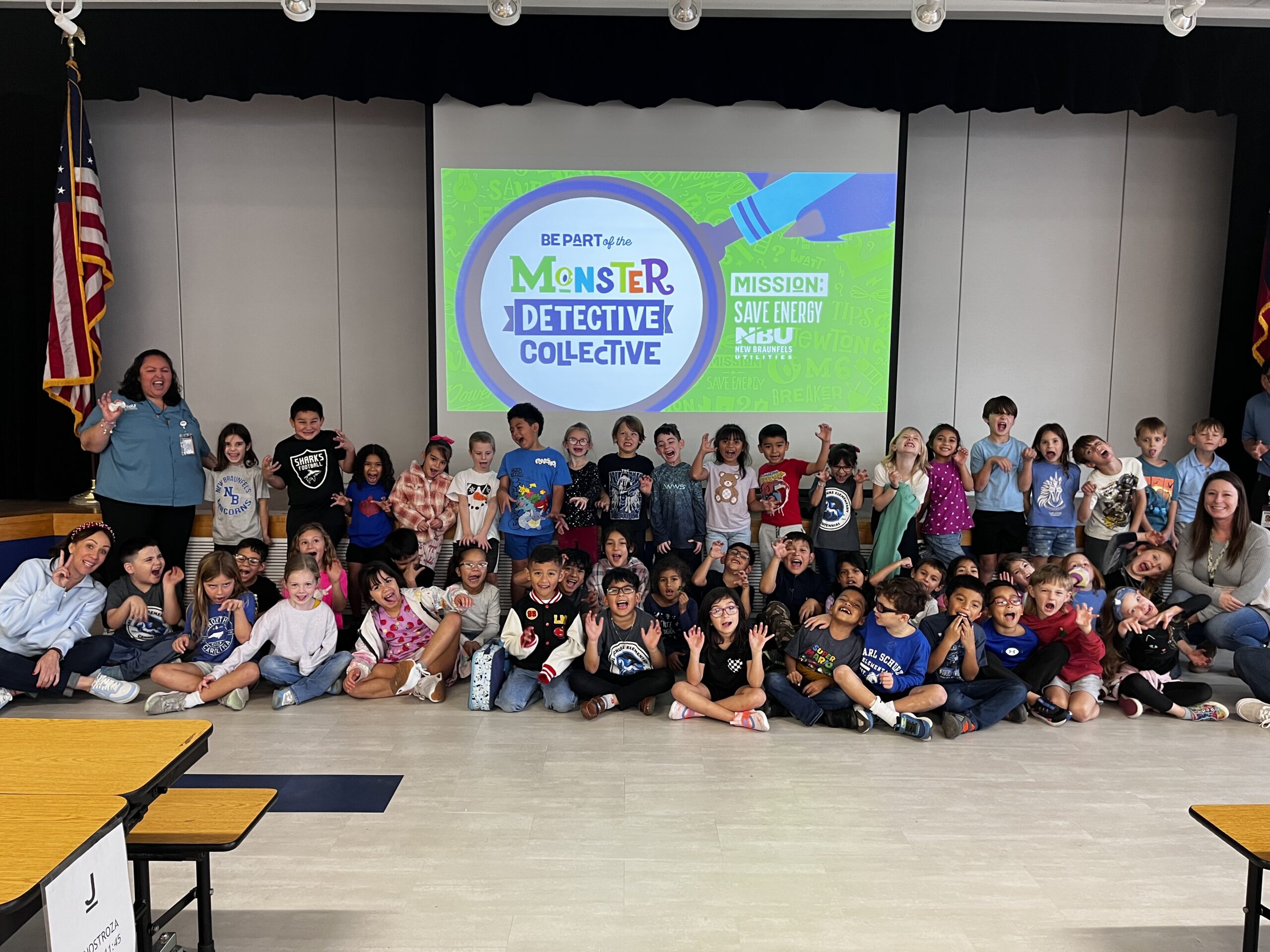 Kids and staff smilling for a group picture during a monster detective presentation