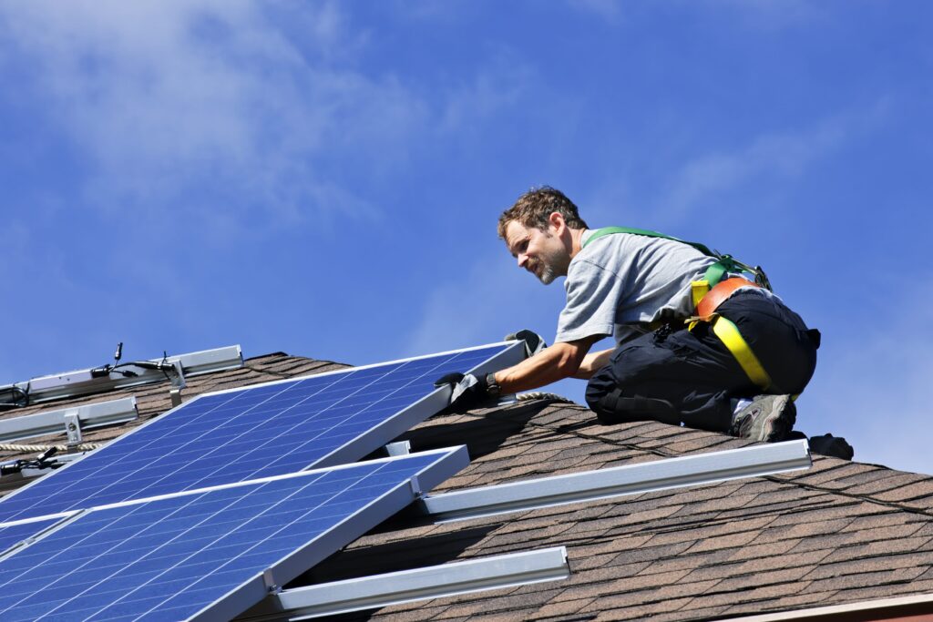 Man installing solar panels onto residential roof