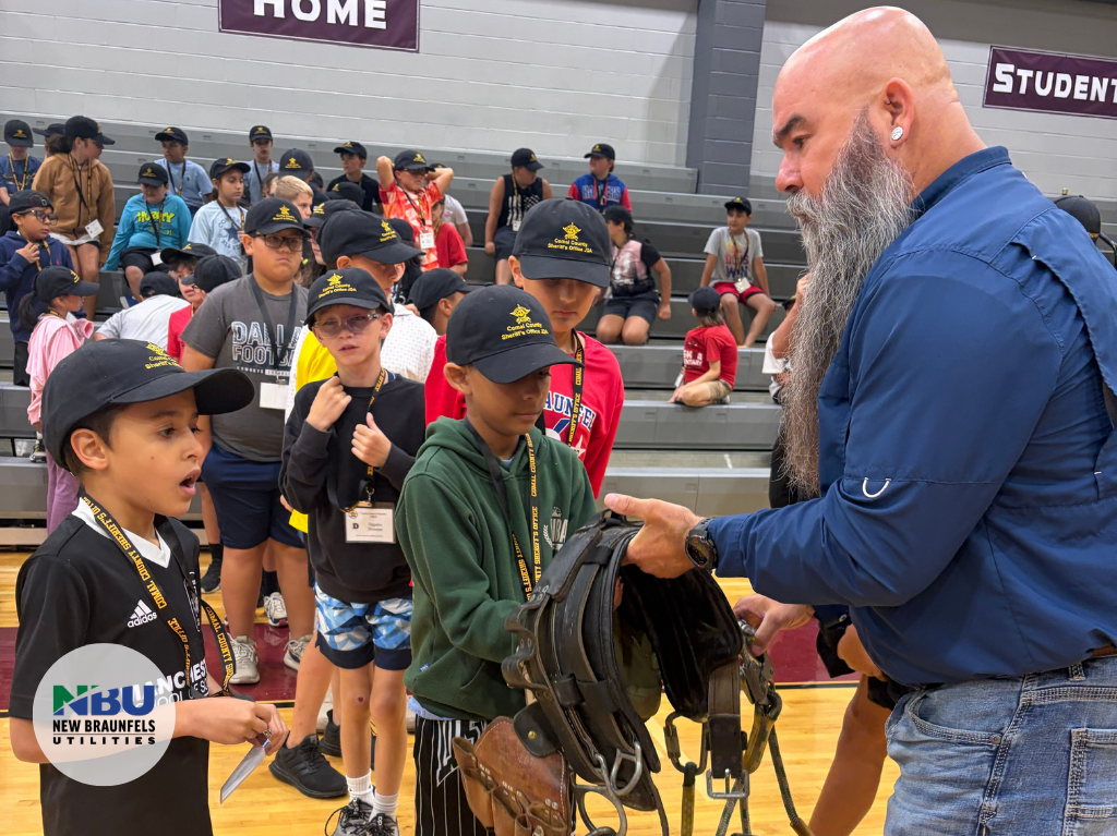 NBU Employee shows students up close and personal utility belt worn by linemen,