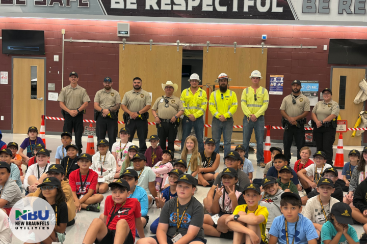 Local law enforcement and NBU Lineman pose for a photo with students in school gym