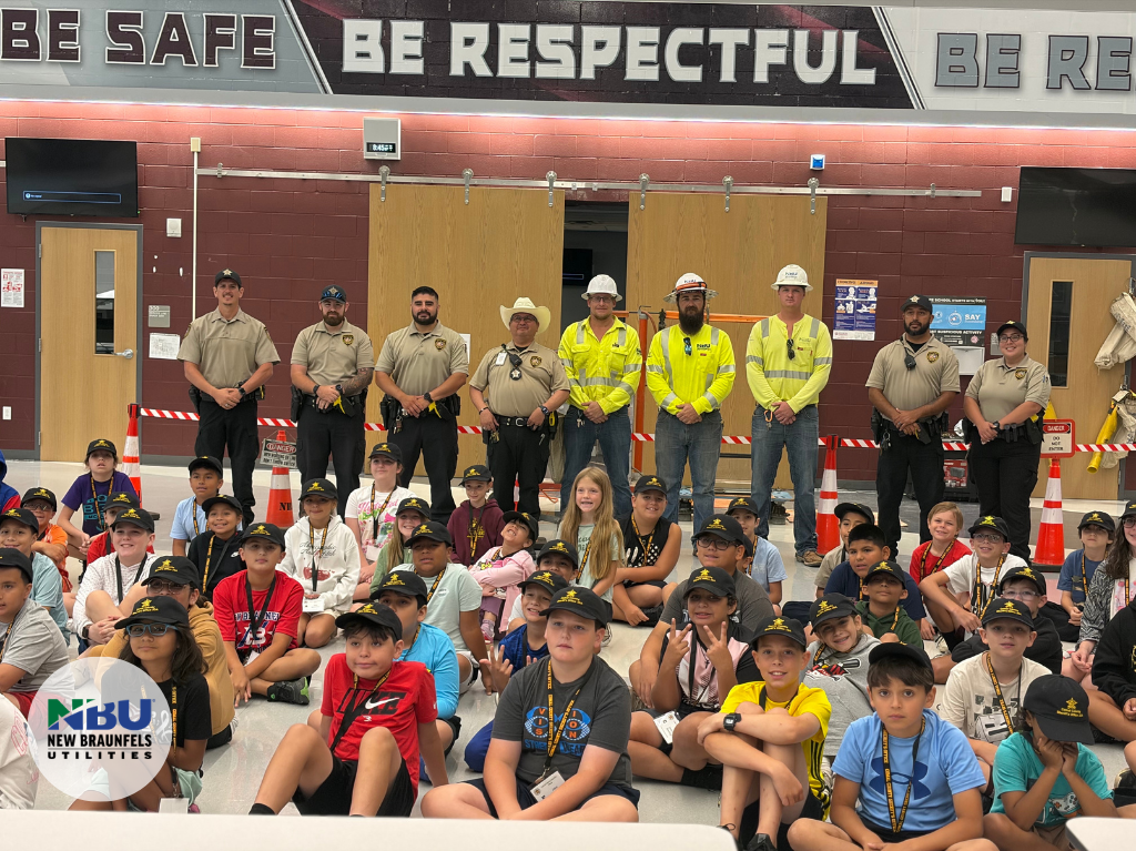 Local law enforcement pose for a photo with NBU Linemen and students in school gym