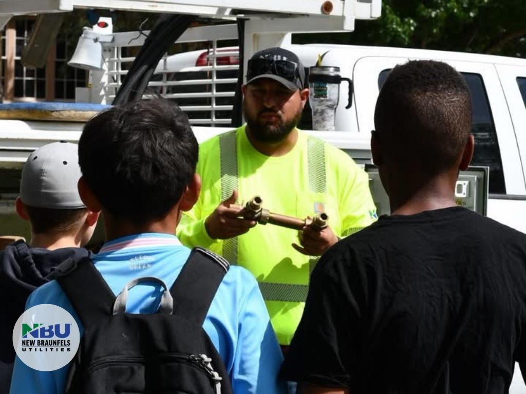 NBU water operation employee shows students the equipment from the water truck.