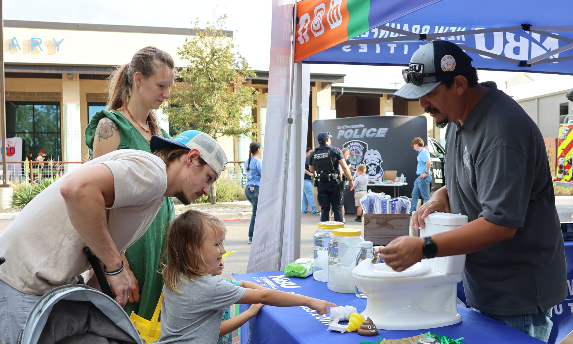 Two parents and two children stop and interact with an NBU employee at a conservation booth