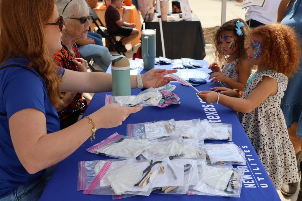 NBU staff hands two young girls DIY butterfly kits