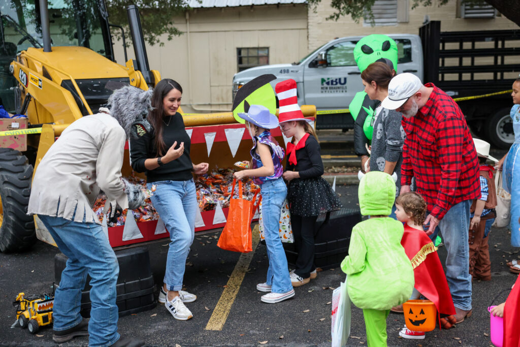 Children in various halloween costumes line up to get candy and treats from NBU employee
