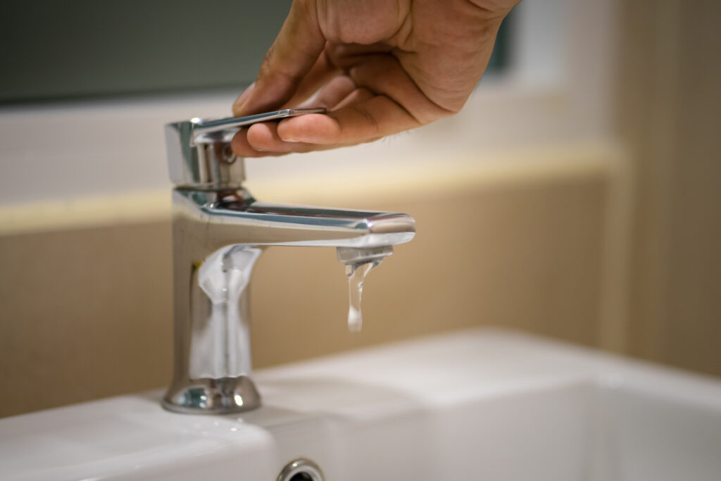Pushing down the valve to turn-off water sink in toilet. Selective focus at hand's finger. Homing activity concept photo.